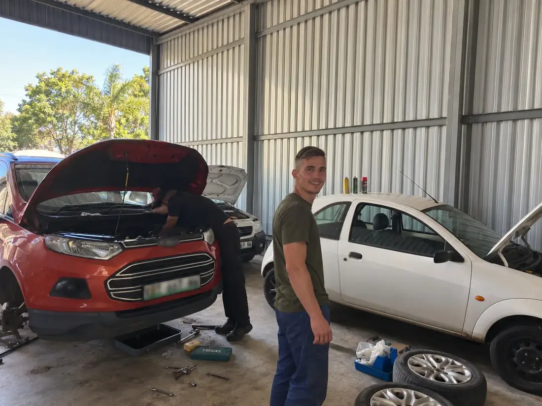 Joe in the workshop with vehicles being worked on